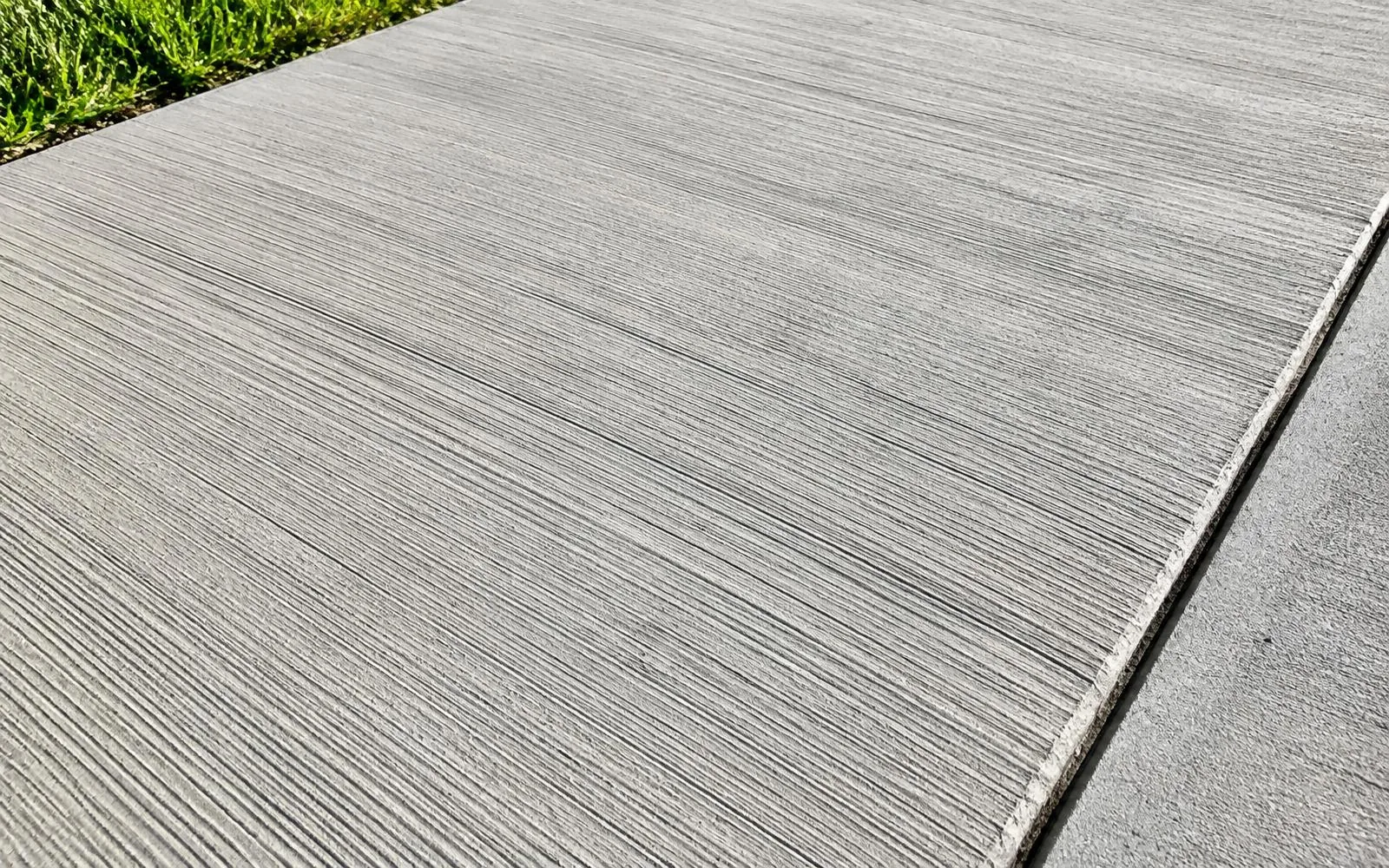 Sunlit close-up of broom-finish concrete texture and a control joint in Pembroke Pines