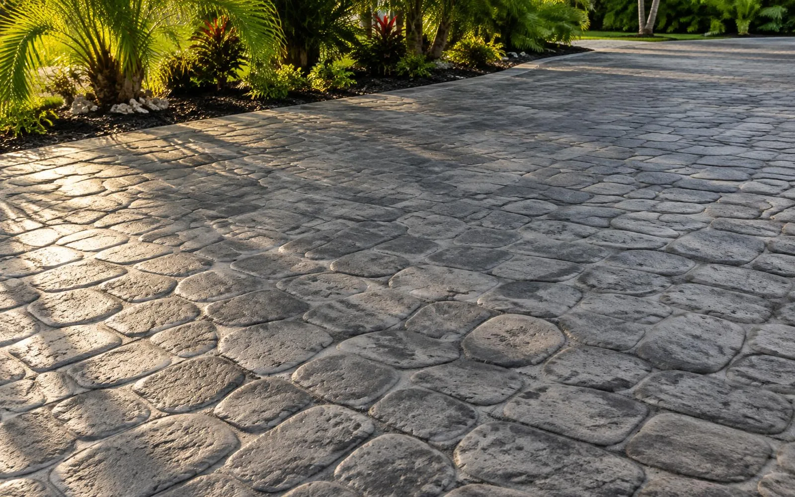 Gray cobblestone-pattern stamped concrete beside tropical landscaping in Pembroke Pines